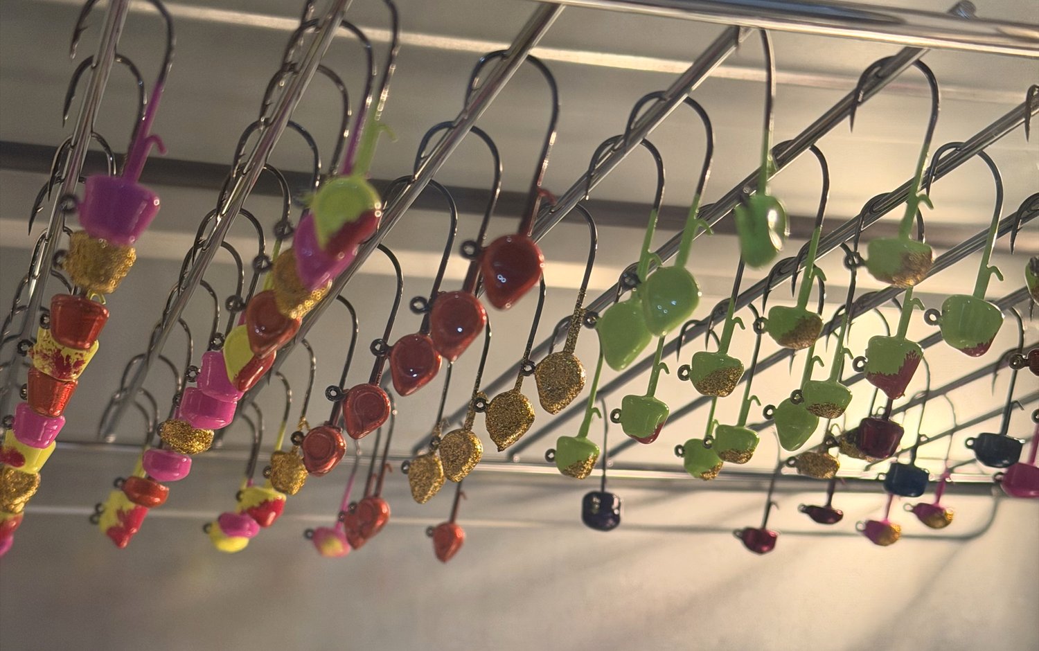 Rows of freshly powder-coated jig heads hanging on racks inside the curing oven